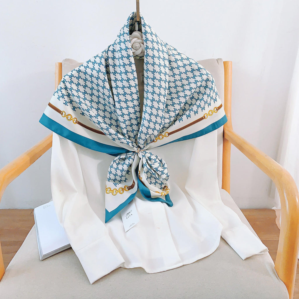 Teal and white silk-satin scarf featuring a monogram pattern and decorative gold chain print