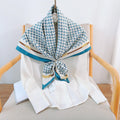 Teal and white silk-satin scarf featuring a monogram pattern and decorative gold chain print