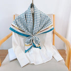 Teal and white silk-satin scarf featuring a monogram pattern and decorative gold chain print