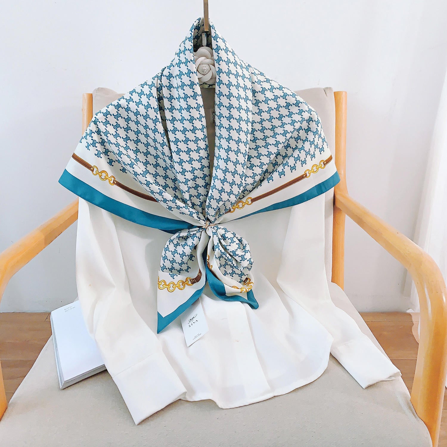 Teal and white silk-satin scarf featuring a monogram pattern and decorative gold chain print