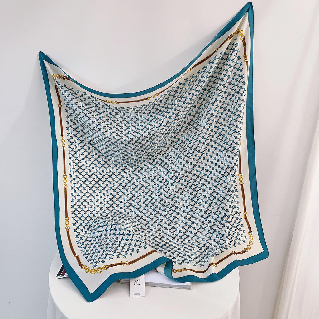Teal and white silk-satin scarf featuring a monogram pattern and decorative gold chain print