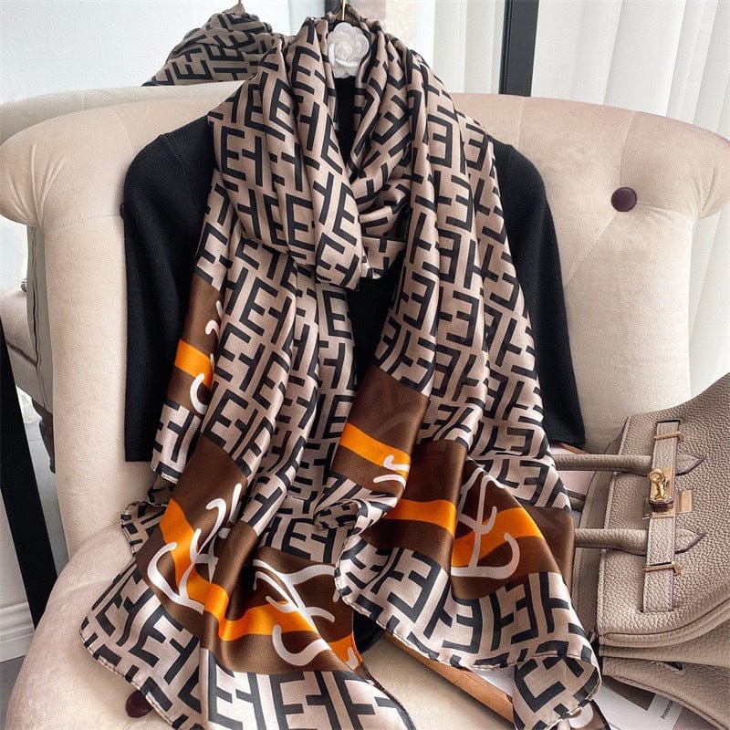 Taupe silk-satin scarf featuring a black monogram letter print and decorative brown and orange stripes