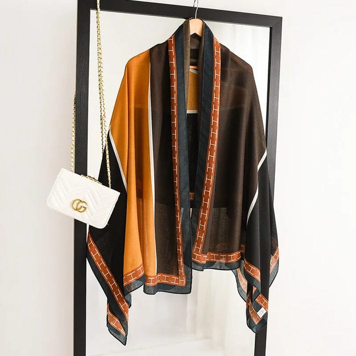 Silk-satin scarf featuring large geometric blocks of brown, orange, and black with a terracotta-colored "H" pattern border