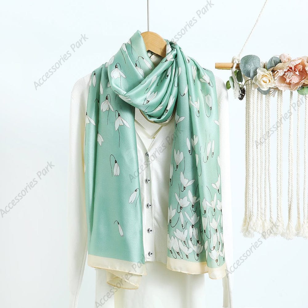 Mint green silk-satin scarf featuring a delicate white snowdrop floral pattern and a cream bordered edge